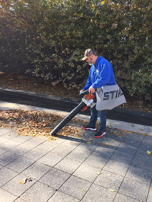 A facilities employee blows leaves